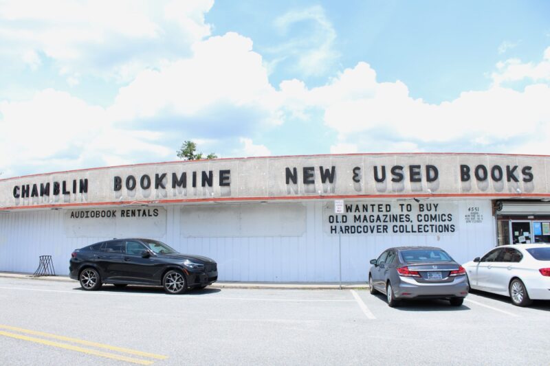 Exterior of Chamblin Bookmine, the largest bookstore in Jacksonville. A large sign says "Chamblin Bookmine - New and Used Books." On the wall are two smaller signs saying "Audiobook rentals" and "Wanted to buy: Old magazines, comics, hardcover collections."